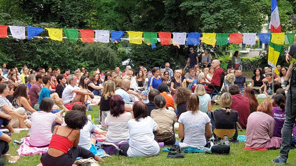 Groupe en méditation bouddhiste en plein air sous drapeaux tibétains colorés