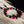Bracelet bouddhiste tibétain en perles rouges, noires et bois, posé sur bois brut