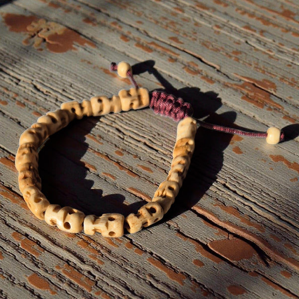 Bracelet bouddhiste en perles sculptées, symbole de la philosophie tibétaine, posé sur bois vieilli