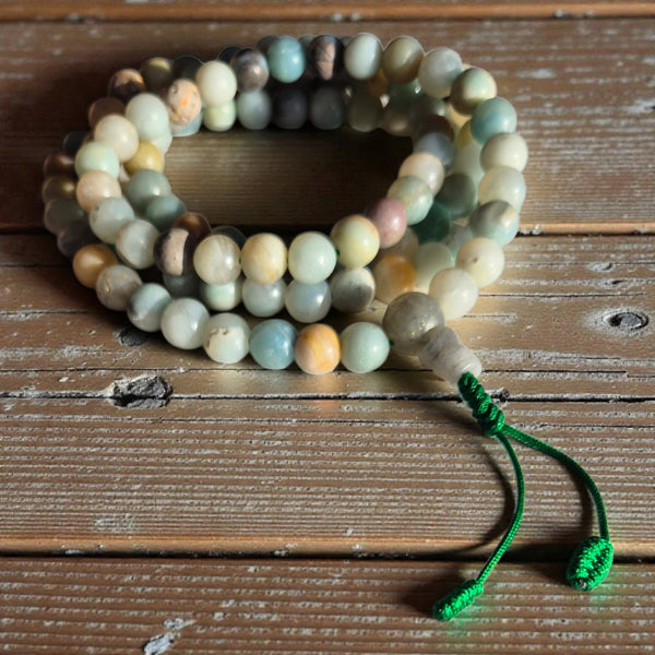 Chapelets bouddhistes en pierres naturelles avec moines tibétains en fond, symboles de méditation et spiritualité