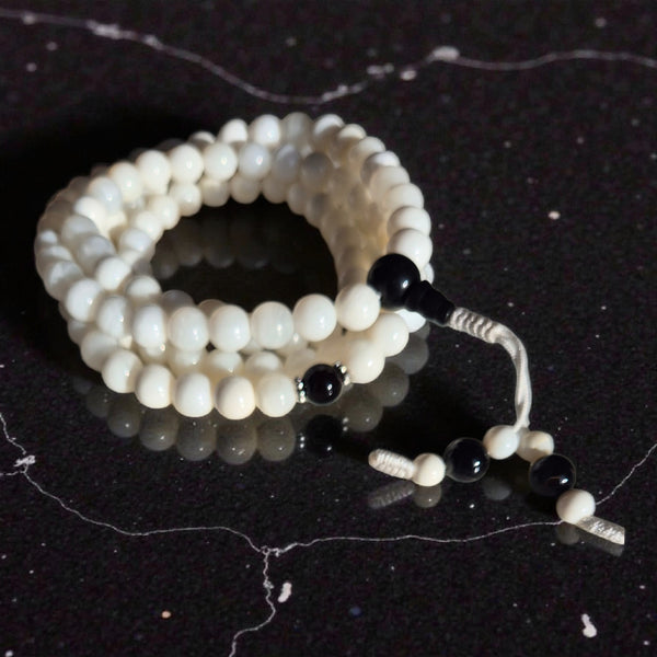 Chapelet bouddhiste blanc et noir pour méditation, perles lisses sur fond marbre