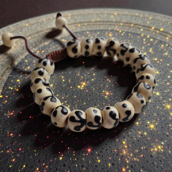 Bracelet bouddhiste en perles naturelles à motifs noirs, symbole de méditation et sagesse tibétaine