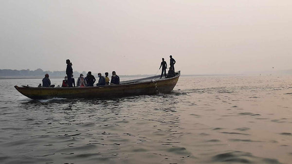 Bateau traditionnel sur un fleuve au crépuscule, passagers et rameurs en silhouette