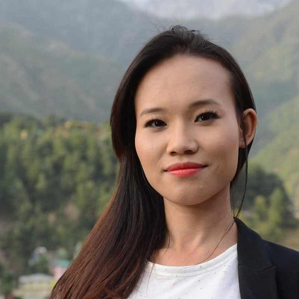 Femme souriante en Himalaya, lien avec la philosophie bouddhiste tibétaine et méditation