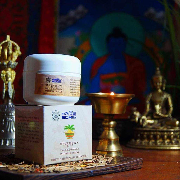 Crème anti-vitiligo tibétaine Sorig Pak-Juk-Da-Ma-Ra, soin naturel avec statuettes bouddhistes et lampe à huile