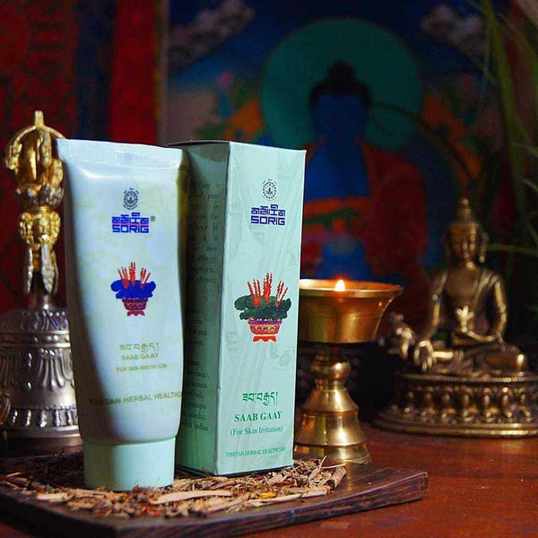 Crème Saab Gaay pour irritation cutanée, soin naturel tibétain avec statuettes bouddhistes et lampe à huile