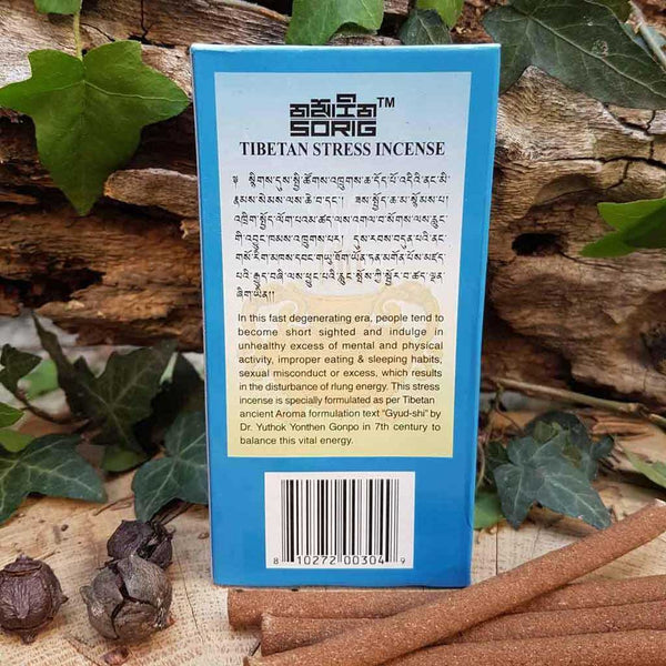 Encens tibétain pour le stress, boîte bleue avec texte en tibétain et anglais, sur fond naturel avec feuilles et bâtonnets