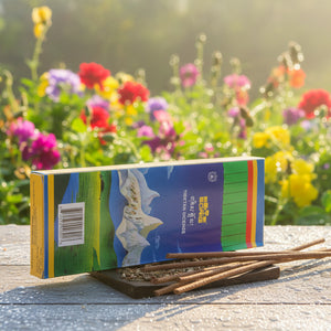 Encens tibétain naturel pour méditation, boîte colorée sur bois avec fleurs en arrière-plan