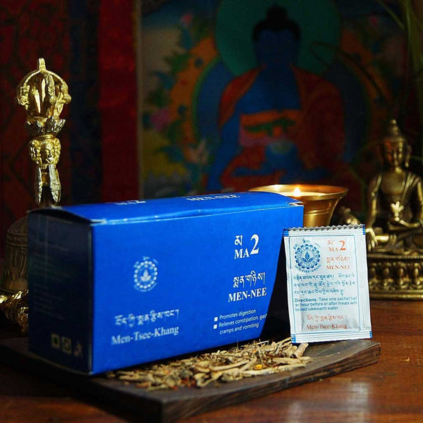 Boîte de Men-Tsee-Khang MA2 pour digestion, avec sachet et herbes, devant thangka bouddhiste et objets tibétains