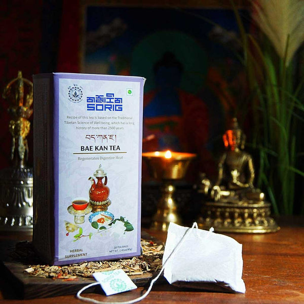 Thé Bae Kan tibétain pour la digestion, sachet et boîte sur fond de bouddha et bougie, médecine naturelle