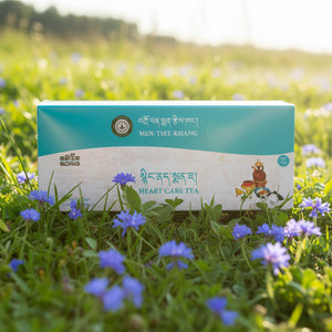 Boîte de thé Heart Care Tea Men-Tsee-Khang dans un champ de fleurs bleues, produits de médecine tibétaine naturelle