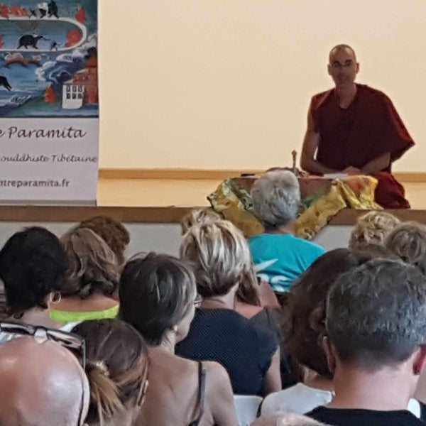 Lama Samten enseigne la philosophie bouddhiste tibétaine lors d'une conférence devant un public attentif.