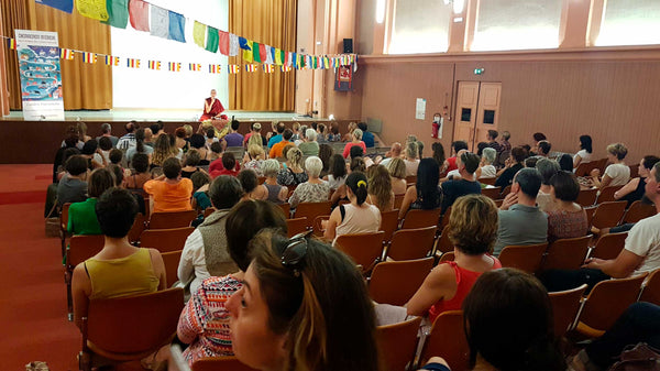 Conférence sur la méditation bouddhiste avec drapeaux tibétains et public attentif