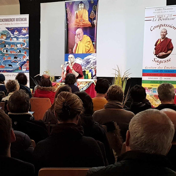 Conférence sur la méditation bouddhiste tibétaine avec Lama Samten devant un public, affiches sur compassion et sagesse