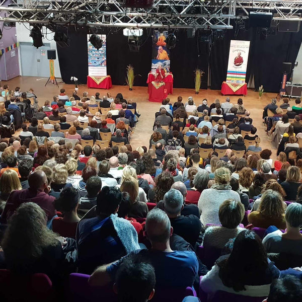 Conférence sur la méditation bouddhiste avec Lama Samten devant un public attentif, décorée de drapeaux tibétains.