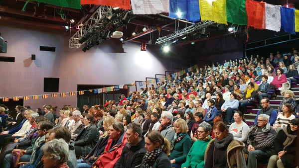 Auditoire lors d'une conférence sur la méditation bouddhiste avec drapeaux tibétains