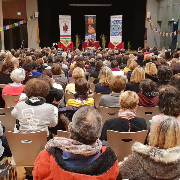 Conférence sur la méditation bouddhiste avec Lama Samten devant un public attentif, drapeaux tibétains et affiches philosophiques