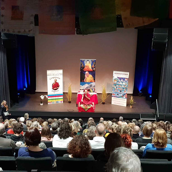 Conférence sur la méditation bouddhiste avec Lama Samten devant public, drapeaux tibétains et livres philosophie
