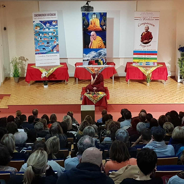 Conférence de méditation bouddhiste tibétaine avec Lama Samten devant public, bannières sur compassion et sagesse