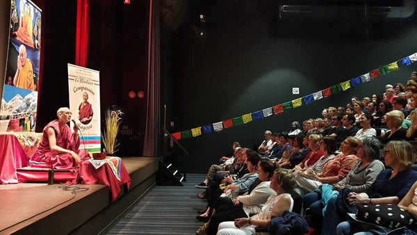 Conférence sur la méditation bouddhiste avec Lama Samten, drapeaux tibétains et public attentif