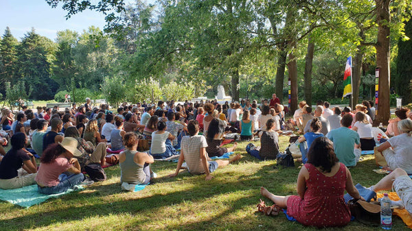 Groupe en méditation bouddhiste en plein air, sous les arbres, avec drapeaux tibétains