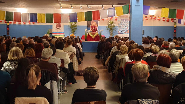 Conférence de méditation bouddhiste avec drapeaux tibétains et public attentif