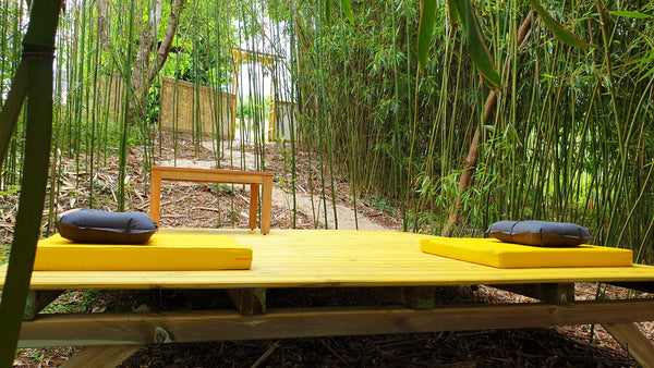 Tapis de méditation jaune et coussins dans un jardin de bambous pour la pratique bouddhiste