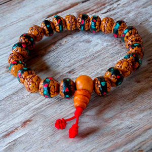 Bracelet bouddhiste en perles naturelles avec motifs colorés et nœud rouge, symbole de méditation et culture tibétaine
