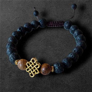 Bracelet bouddhiste en lave et bois avec nœud mystique doré, symbole de la philosophie tibétaine