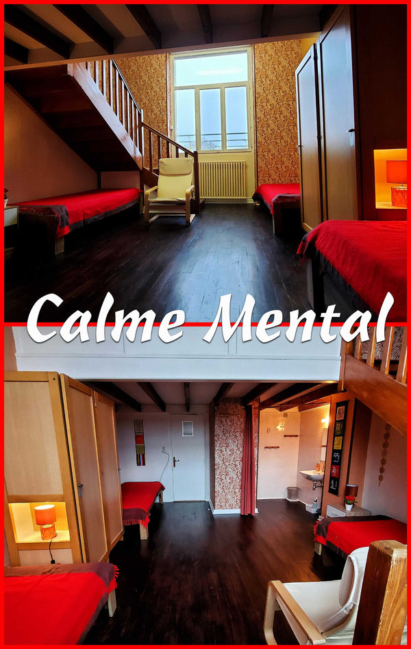 Chambre calme avec lits rouges, parquet sombre et escalier, idéale pour méditation et sérénité mentale