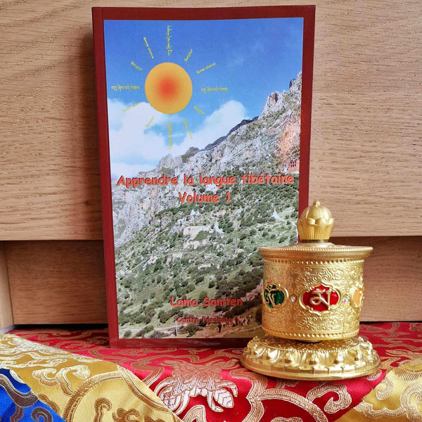 Livre Apprendre la langue tibétaine Volume 1 par Lama Samten avec moulin à prières doré sur tissu traditionnel