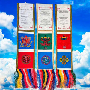 Drapeaux de prière tibétains avec symboles bouddhistes et citations inspirantes sur fond de ciel bleu