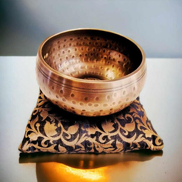 Bol tibétain en cuivre avec motifs, posé sur coussin brodé pour méditation et bien-être