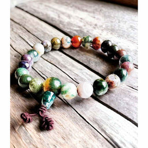 Bracelet bouddhiste en pierres naturelles multicolores sur bois rustique