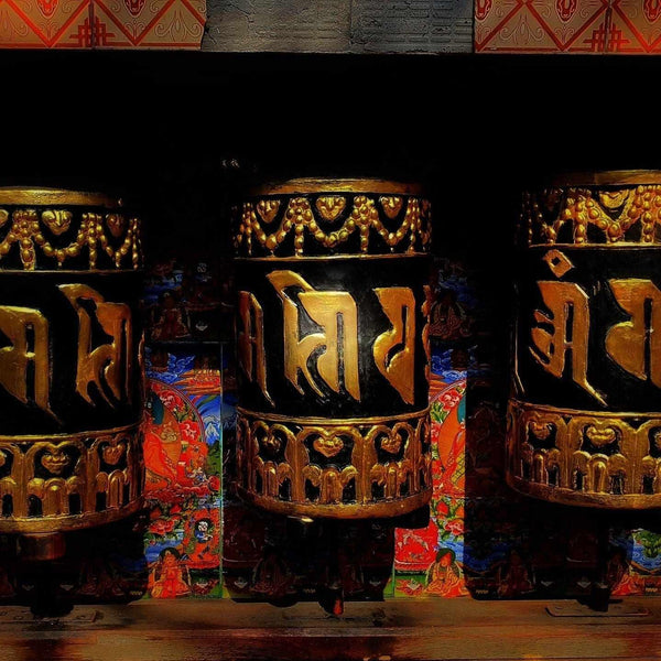 Roues à prières tibétaines ornées de calligraphie dorée et motifs traditionnels
