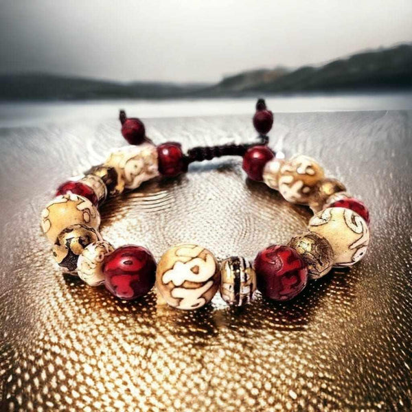 Bracelet bouddhiste tibétain avec perles gravées et rouges, symboles de méditation et sagesse