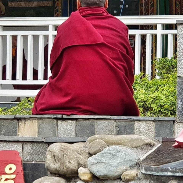 Moine bouddhiste en robe rouge méditant, culture tibétaine et philosophie bouddhiste