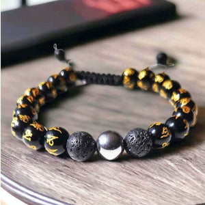 Bracelet bouddhiste avec perles noires gravées d'or, pierres de lave et obsidienne, symboles tibétains