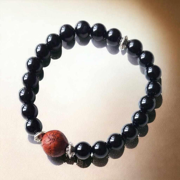 Bracelet bouddhiste en perles noires avec perle centrale en rudraksha, symbole de méditation et philosophie tibétaine