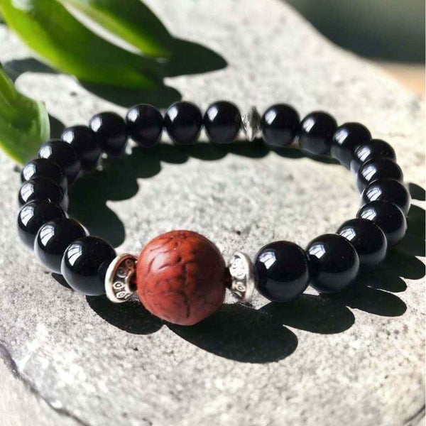 Bracelet bouddhiste en perles noires avec perle centrale en bois sculpté, symbole de méditation et sagesse tibétaine