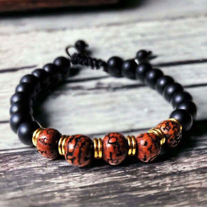 Bracelet bouddhiste en perles noires et rouges avec détails dorés, inspiré de la culture tibétaine