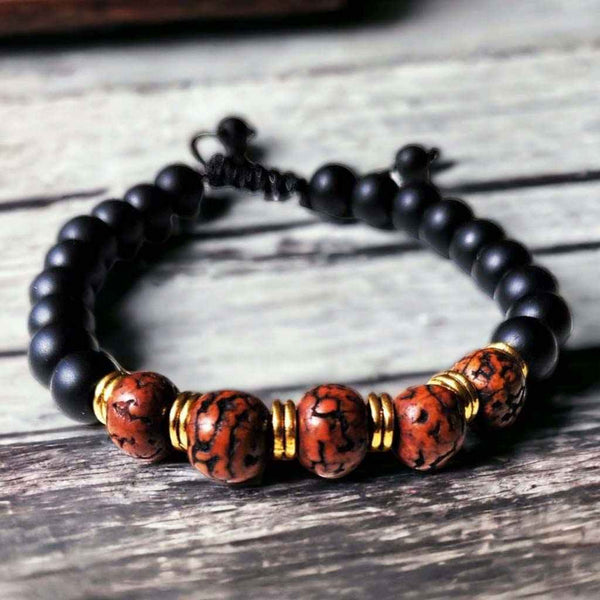 Bracelet bouddhiste en perles noires et rouges avec détails dorés, inspiré de la culture tibétaine
