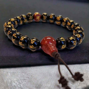 Bracelet bouddhiste tibétain avec perles noires gravées et pendentif rouge, symbole de méditation et spiritualité