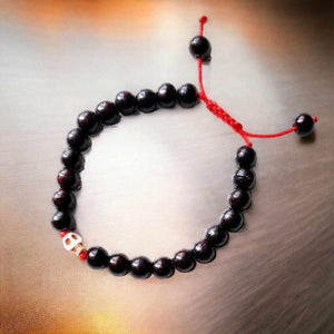Bracelet bouddhiste en perles noires avec crâne et cordon rouge, symbole de méditation tibétaine