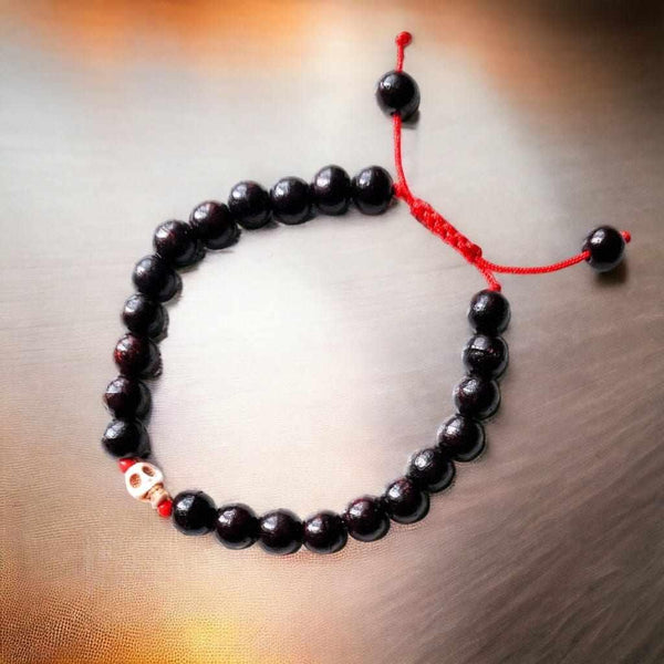 Bracelet bouddhiste en perles noires avec crâne et cordon rouge, symbole de méditation tibétaine