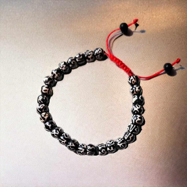 Bracelet bouddhiste avec perles gravées et cordon rouge, symbole de la philosophie tibétaine
