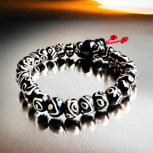 Bracelet bouddhiste tibétain en perles noires et blanches avec nœud rouge, symbole de protection et méditation