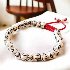 Bracelet bouddhiste à perles spirales noires et blanches avec cordon rouge, symbole de méditation tibétaine