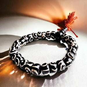 Bracelet bouddhiste en perles d'œil de tigre noir et blanc avec pompon rouge, symbole de protection tibétaine