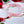 Bracelet en perles roses translucides avec nœud rouge, entouré de roses rouges